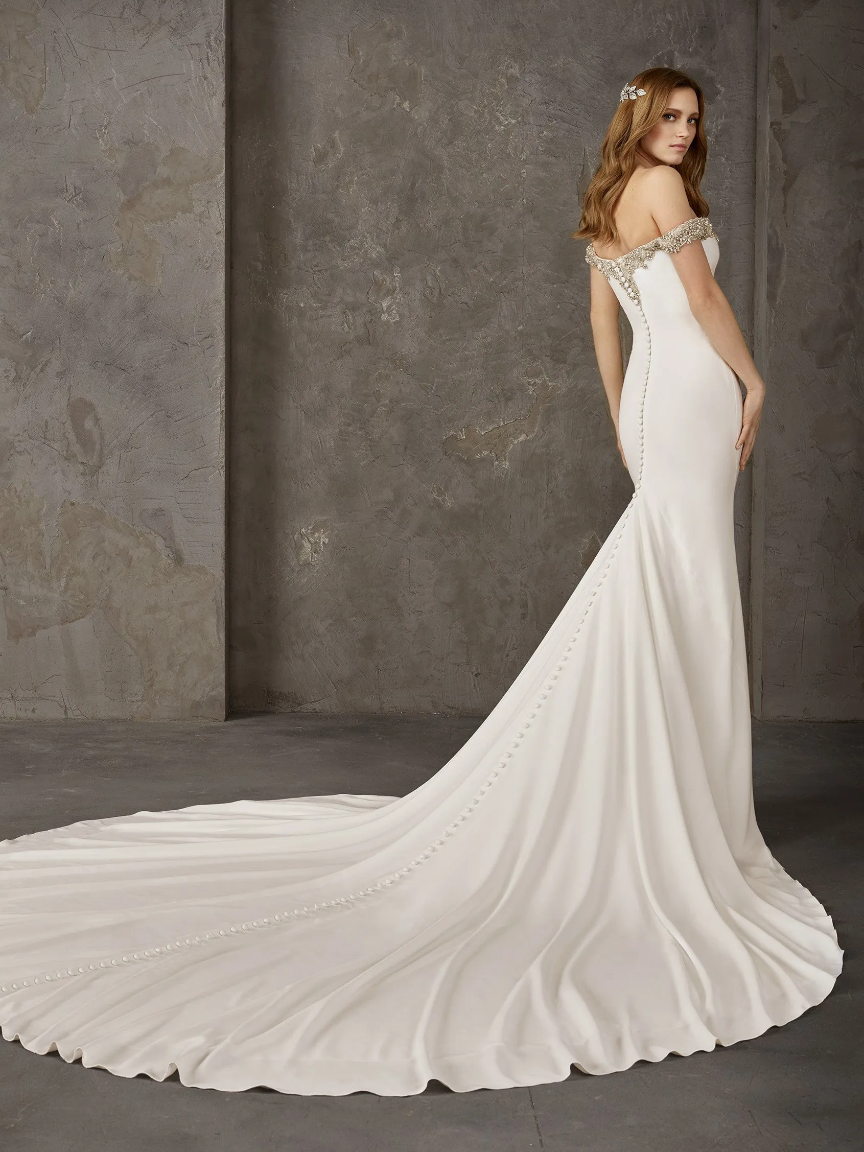 Off-shoulder mermaid wedding dress made entirely in crepe with sparkling gemstone embellishments at the neckline and off-shoulder sleeves.